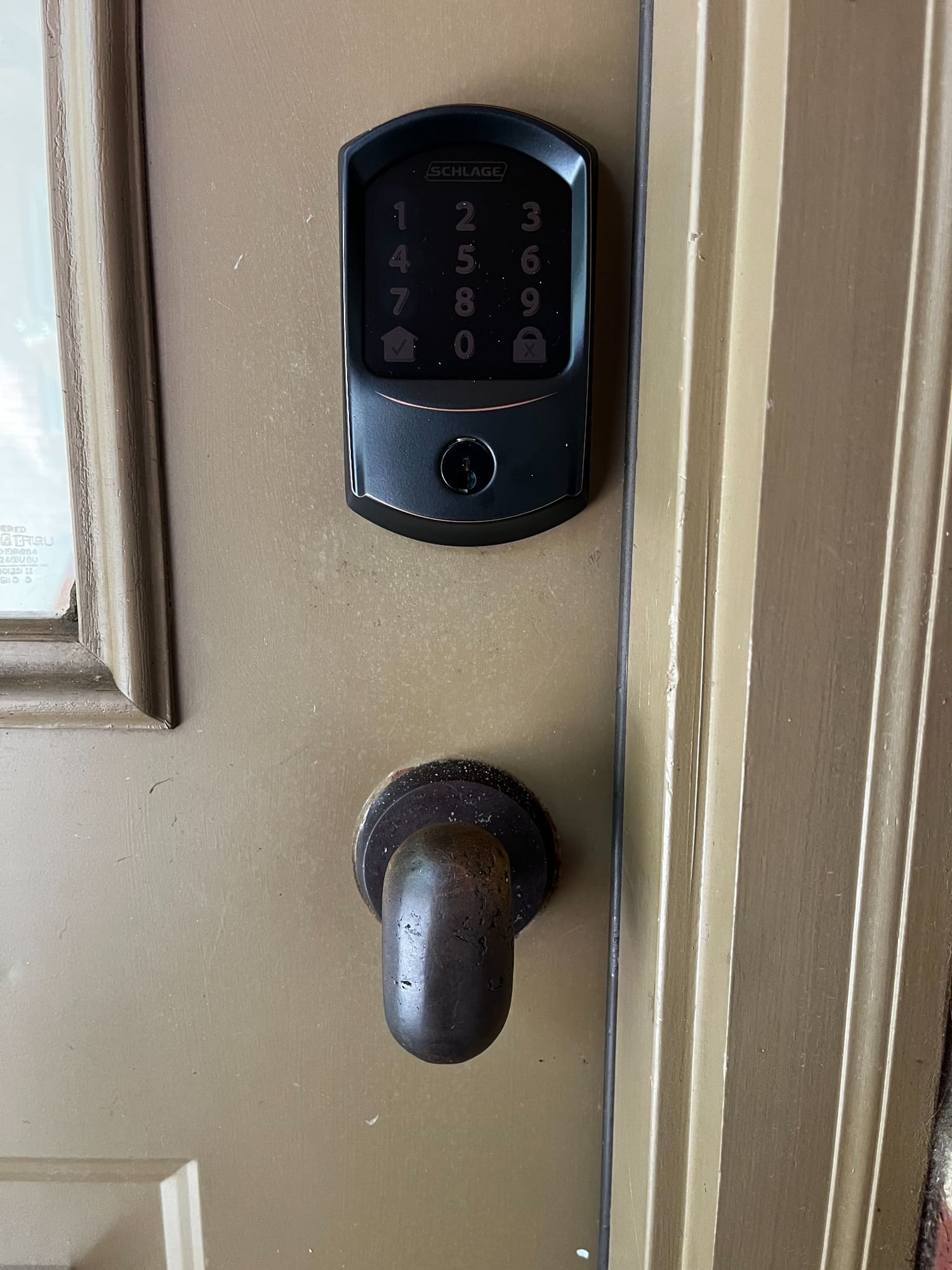 Schlage digital keypad lock mounted on beige door with deadbolt below